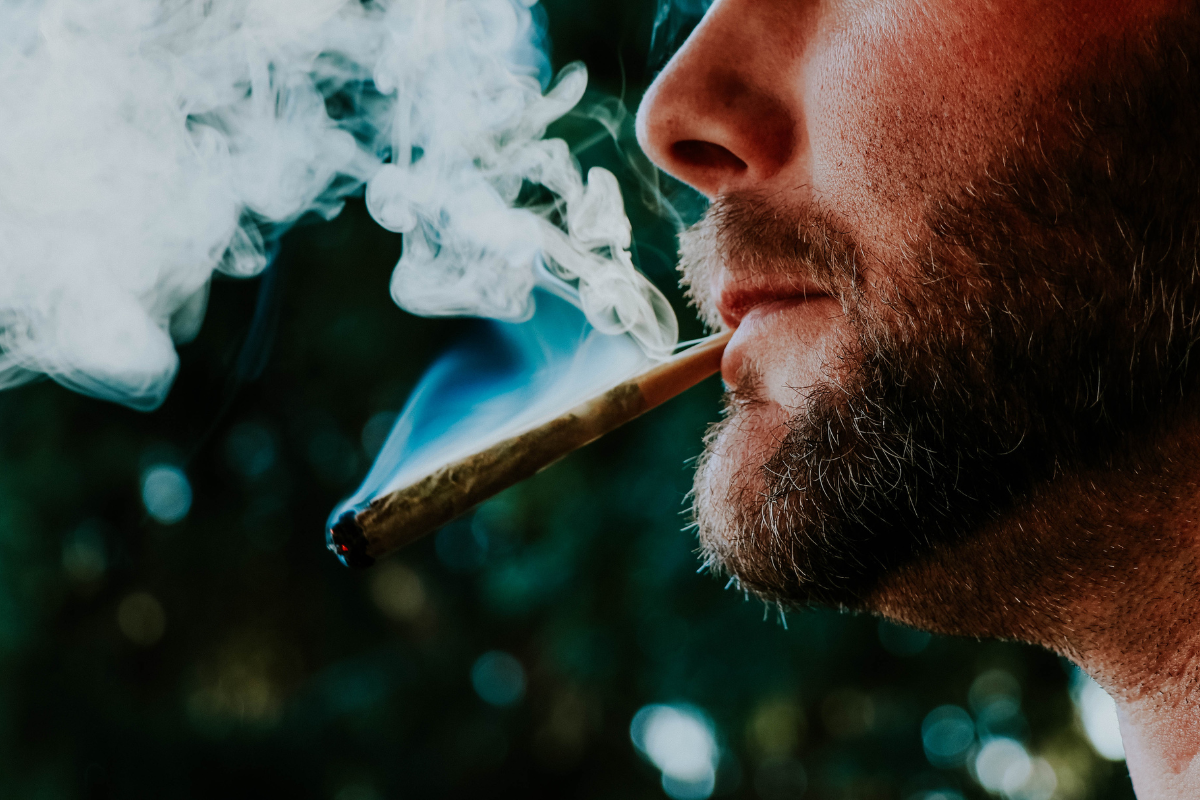 An image of a man smoking a marijuana joint.