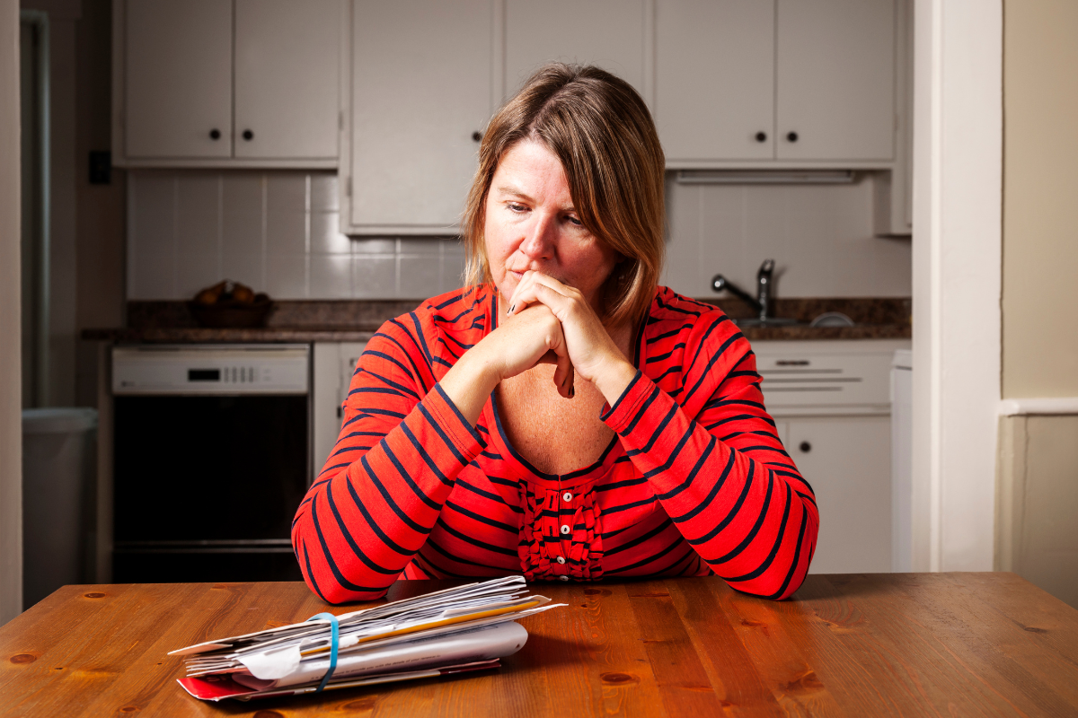 A worried woman looking at her stack of bills.