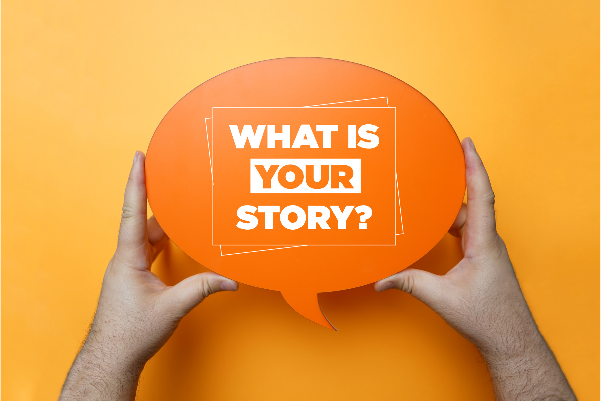An image of hands holding a sign with the words "What is your story?"