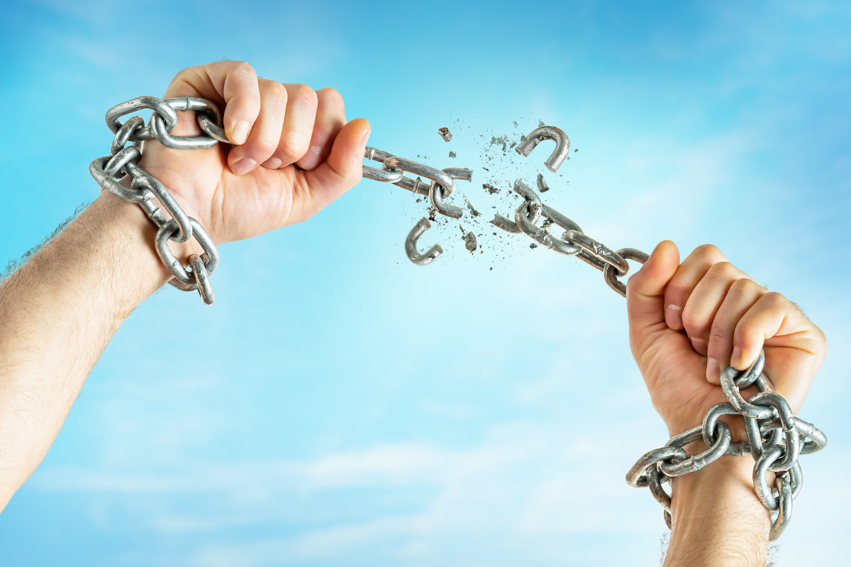 An image of hands breaking free from chains.