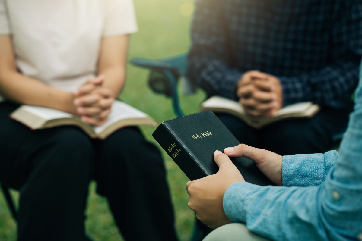 A group of people with one holding the Holy Bible.