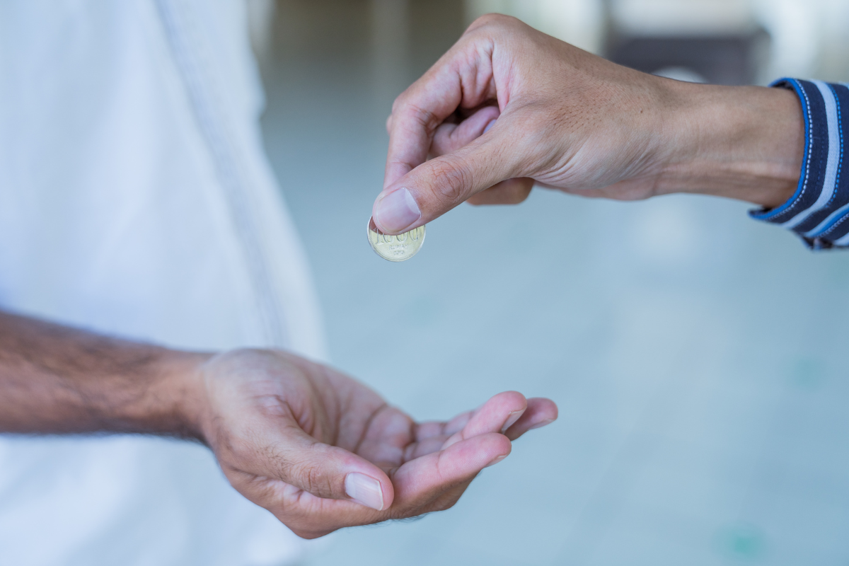 An image of a person giving someone a coin.