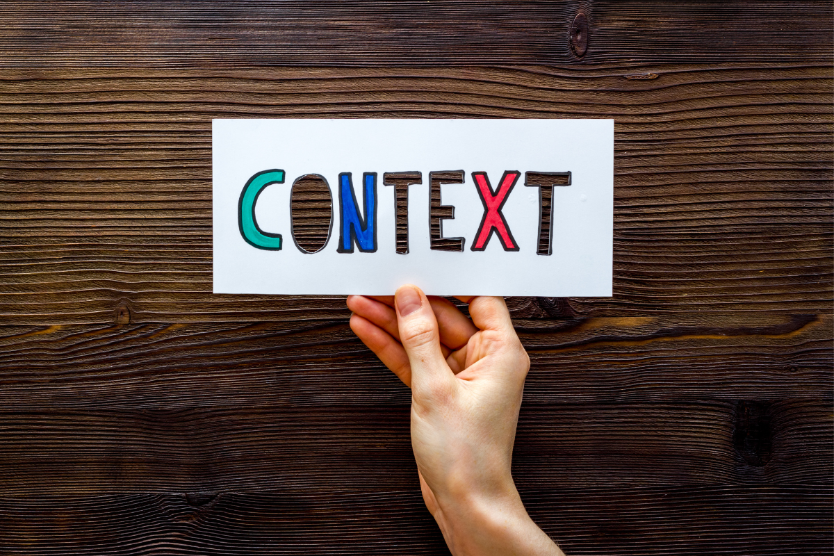 An image of a hand holding a paper cutout with the word CONTEXT.