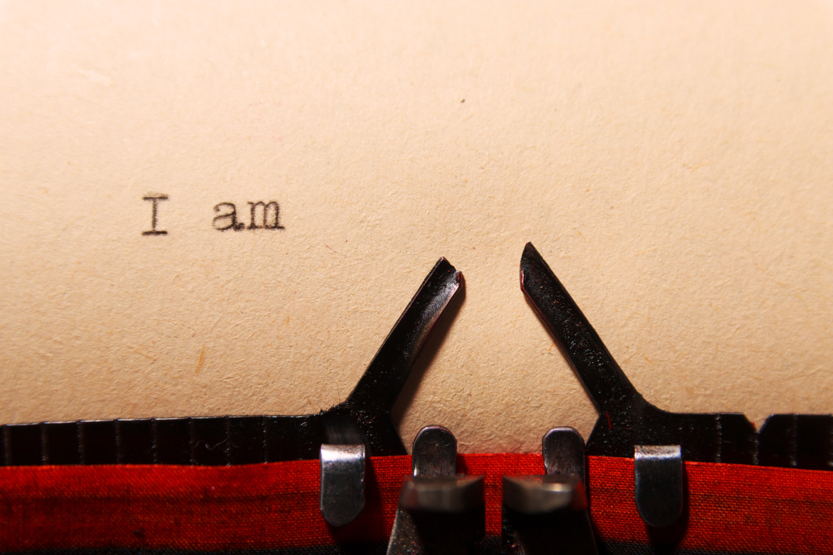 The words 'I am' typed on a paper through a typewriter.