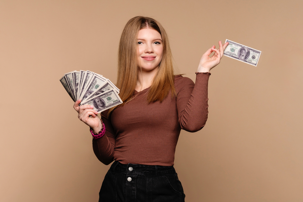 A woman holding a bunch of hundred dollar bills.