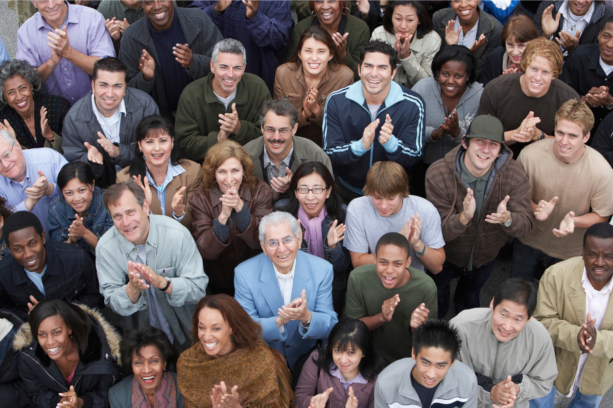 A group of people looking up while clapping their hands.
