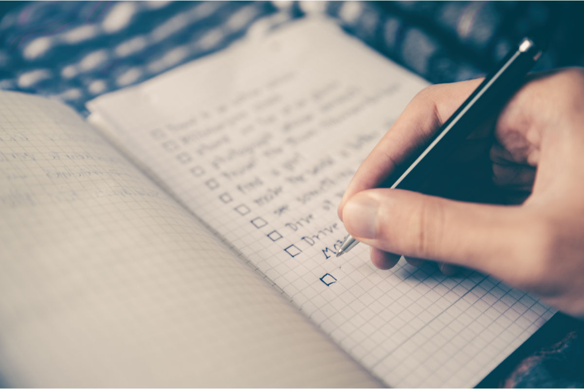A person jotting down a checklist on a notebook.