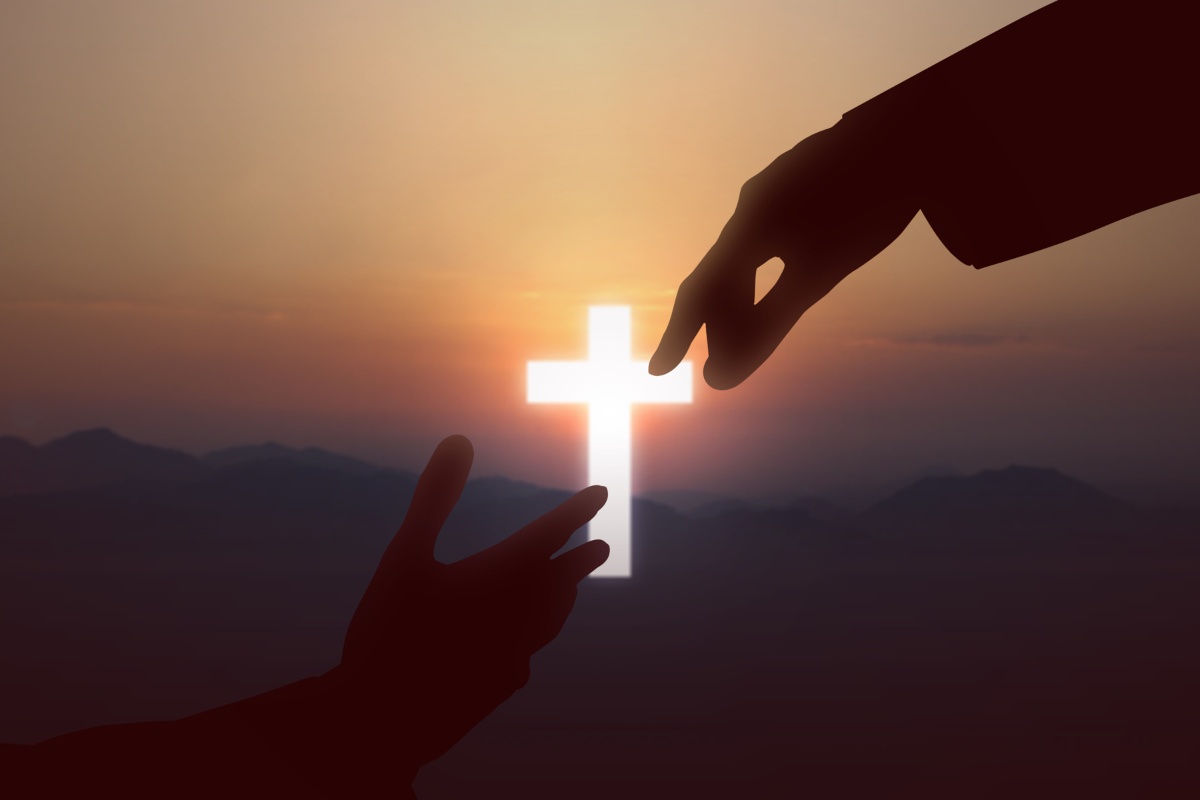 Hands reaching out to each other with a glowing cross behind it.