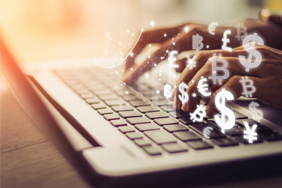 A person typing on a laptop, with different currency symbols.