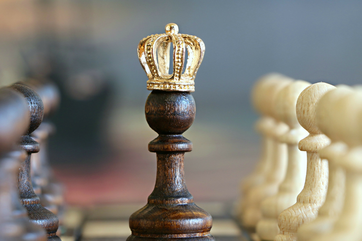 A king chess piece surrounded by pawns.