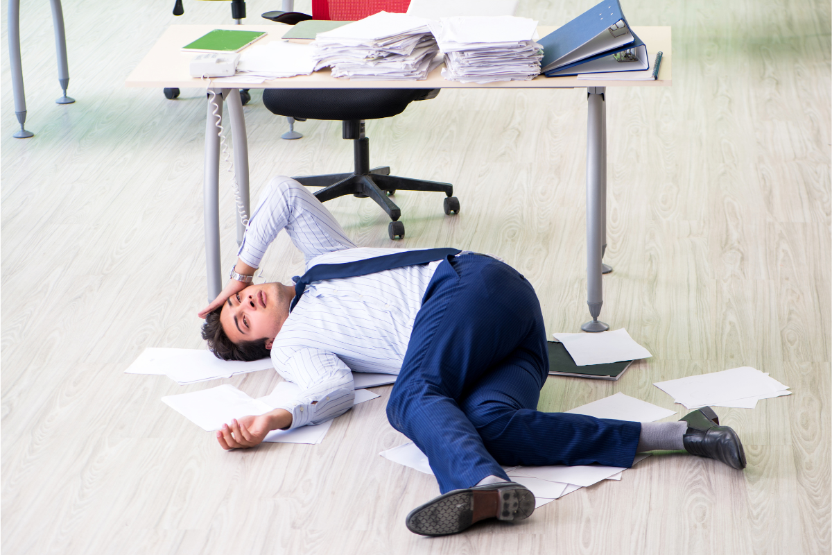 An employee lying down on the floor, exhausted from working tirelessly.