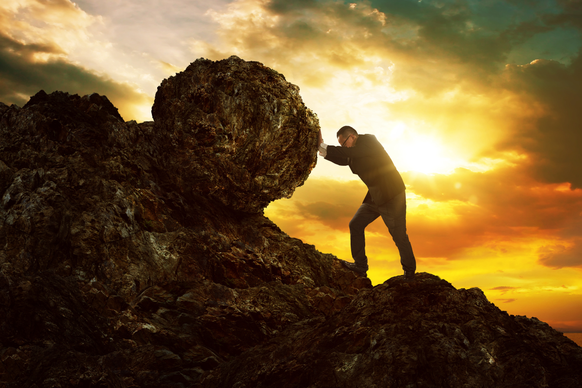 A person pushing a boulder uphill.