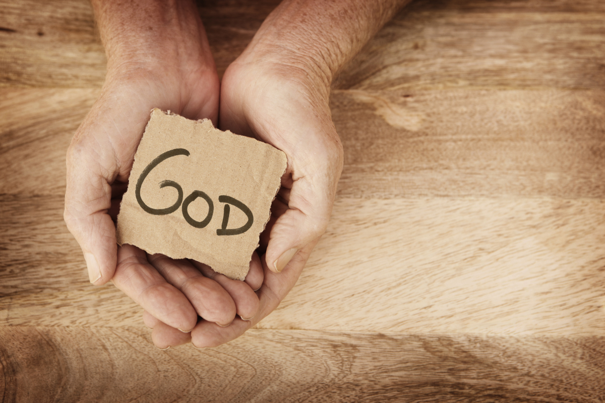The word GOD written on a cutout cardboard, held by hands.
