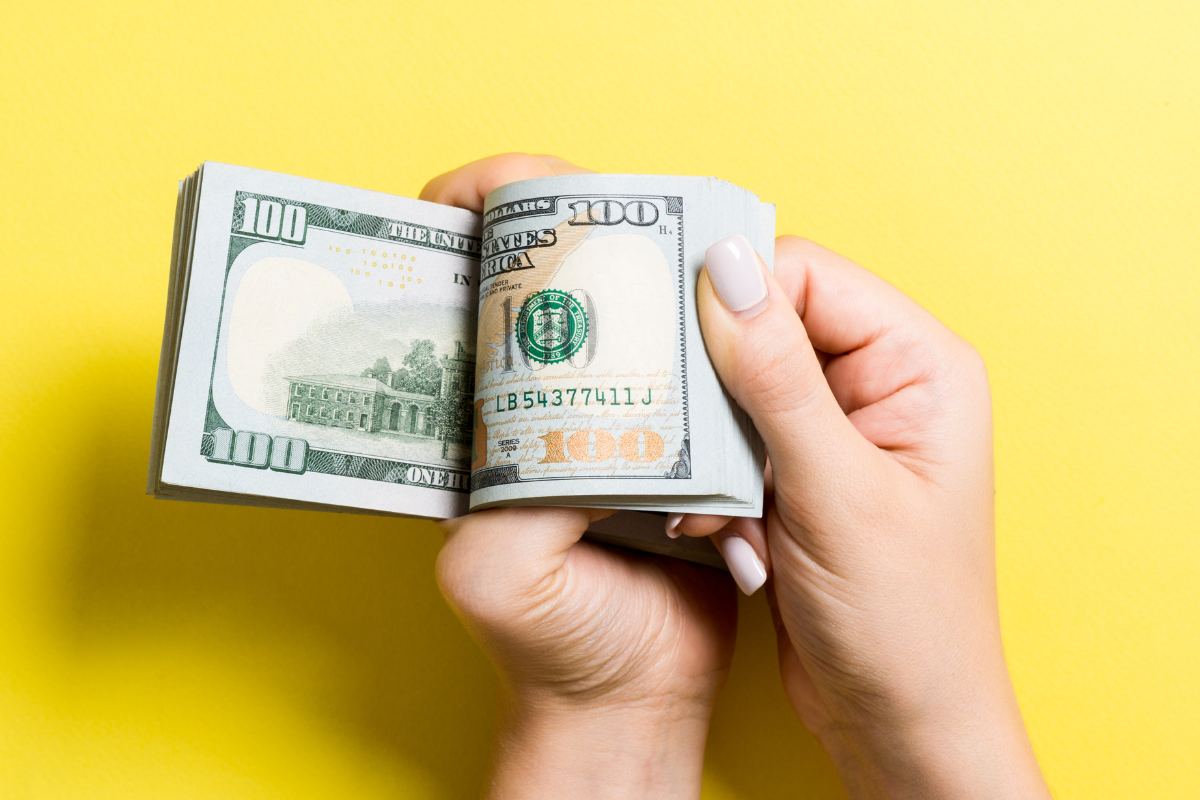 A pair of hands flipping over hundred dollar bills.