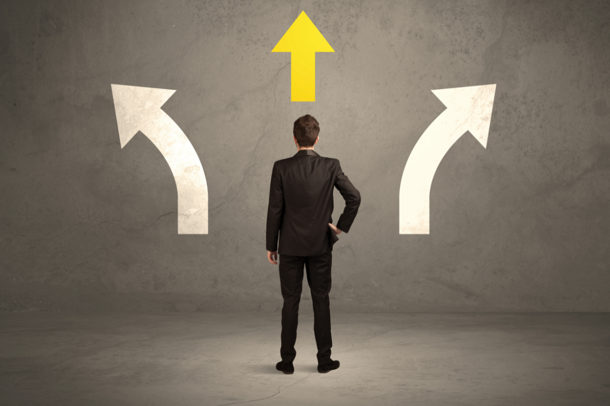 A man in a business suit. looking at three arrows pointing at different directions, symbolizing decision making.