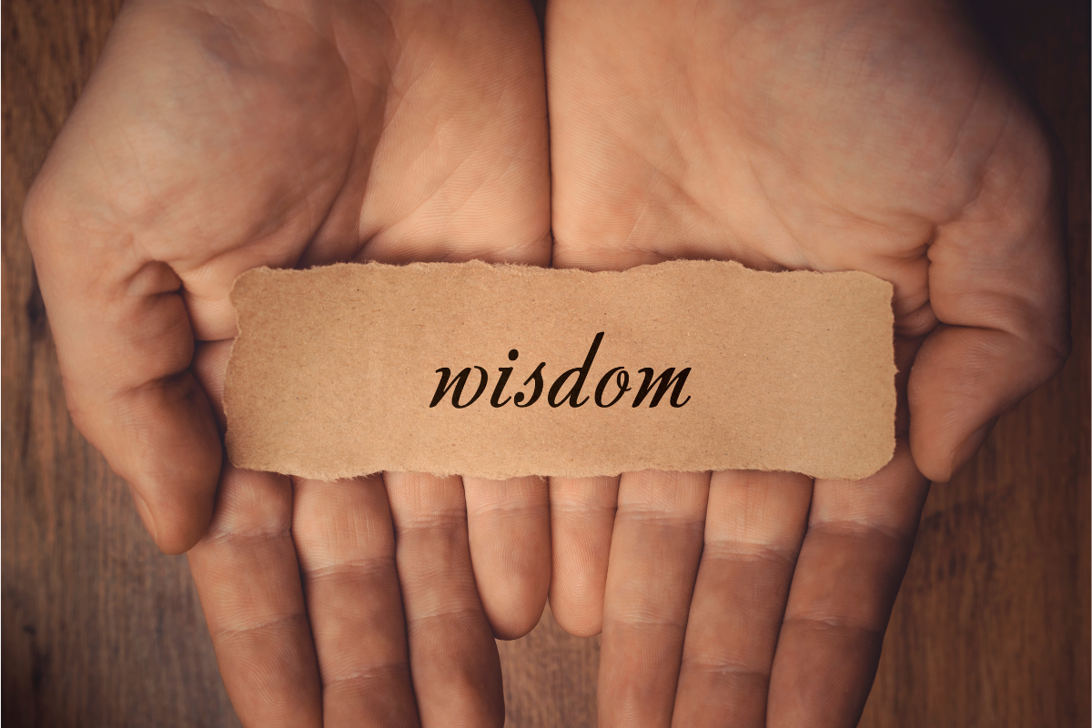 A person holding a piece of paper with the word WISDOM on it.