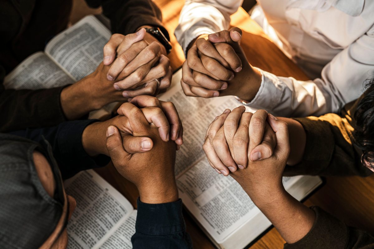 Pairs of hands in prayer during a Bible study session.