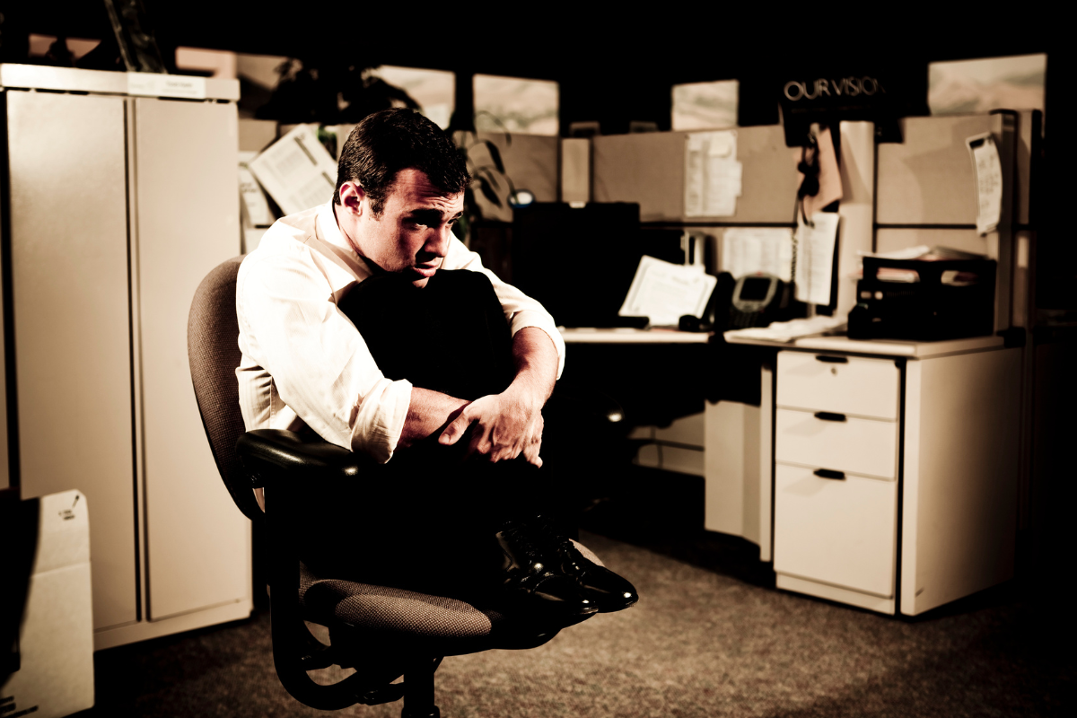 A man looking tired and exhausted at a workplace.