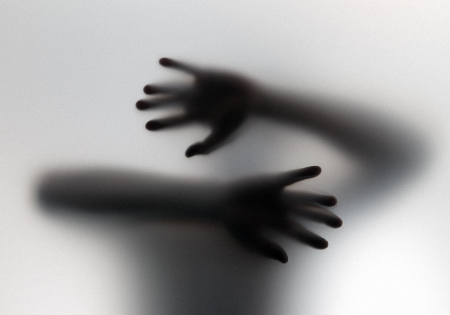 A pair of hands and arms pressing on a plastic sheet, symbolizing fear.