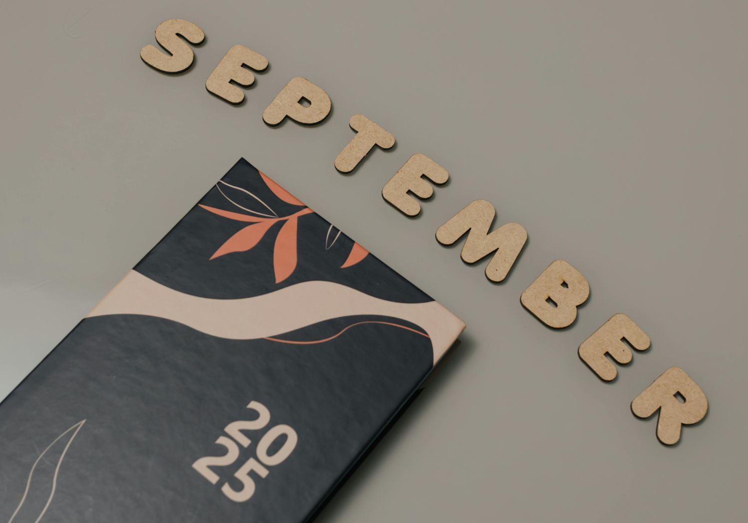 The word September spelled out and a journal with 2025 embossed on it.