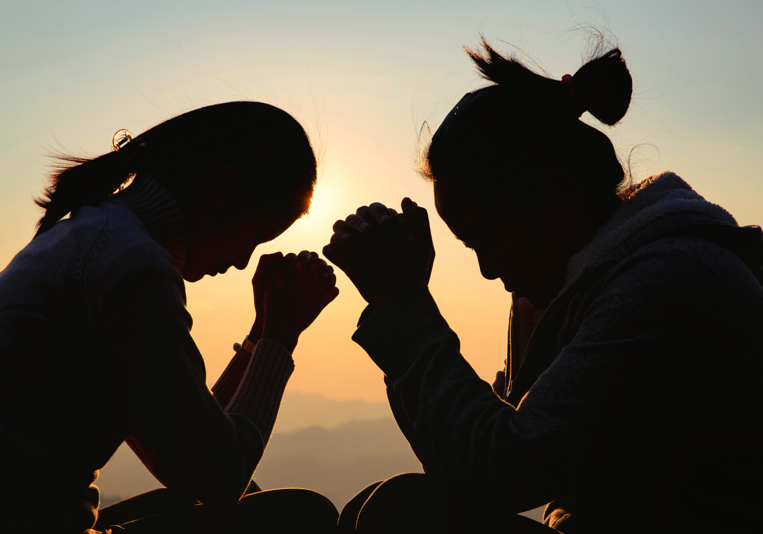 A silhouette of a man and a woman praying together.