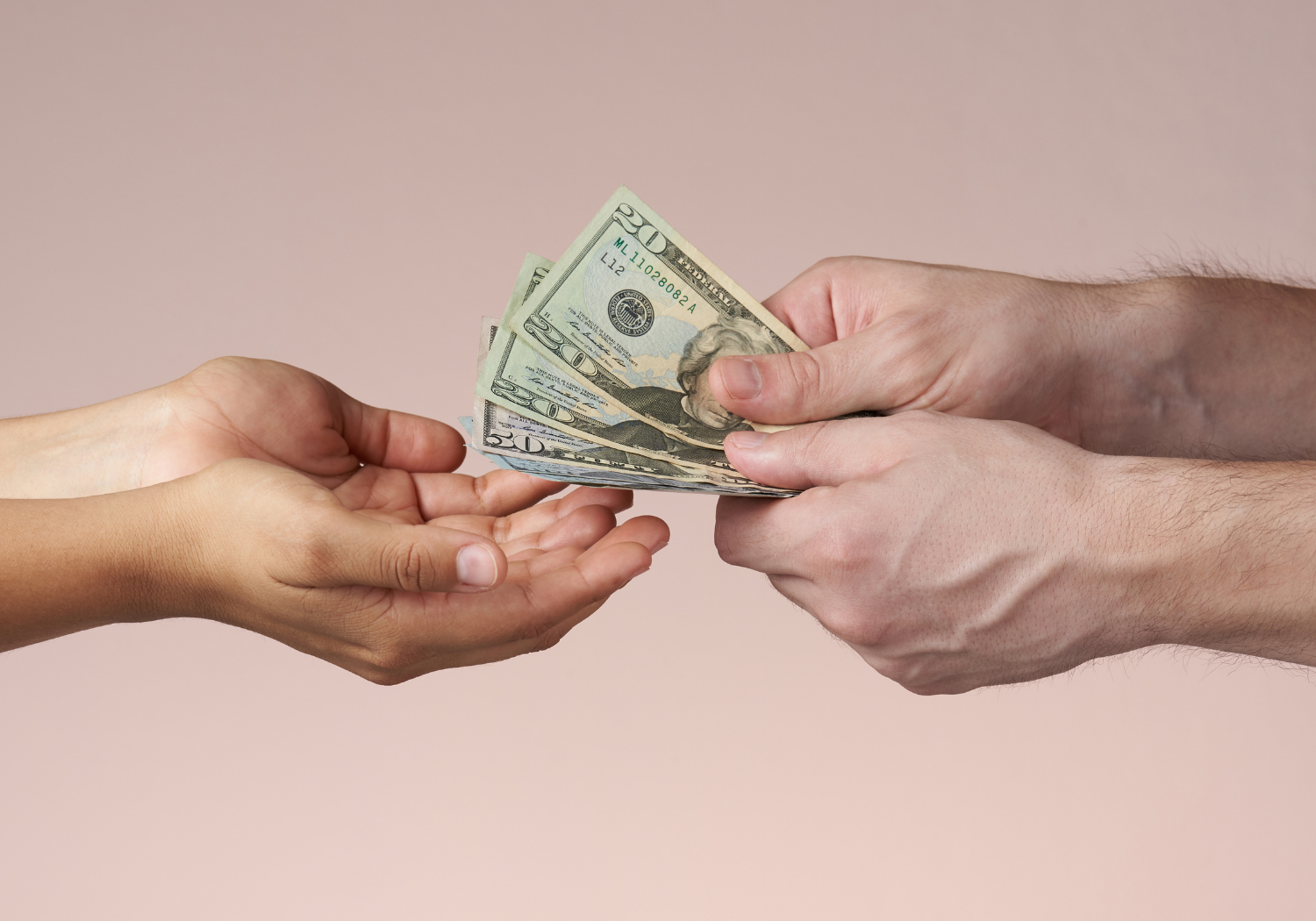 A pair of hands giving out money to another.