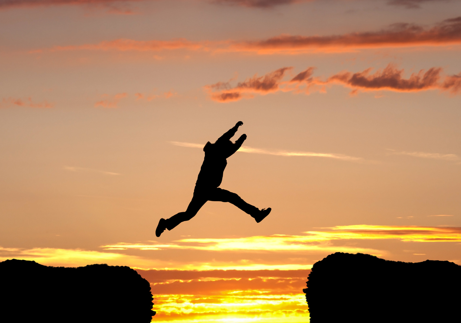 A man jumping from one mountain to another.