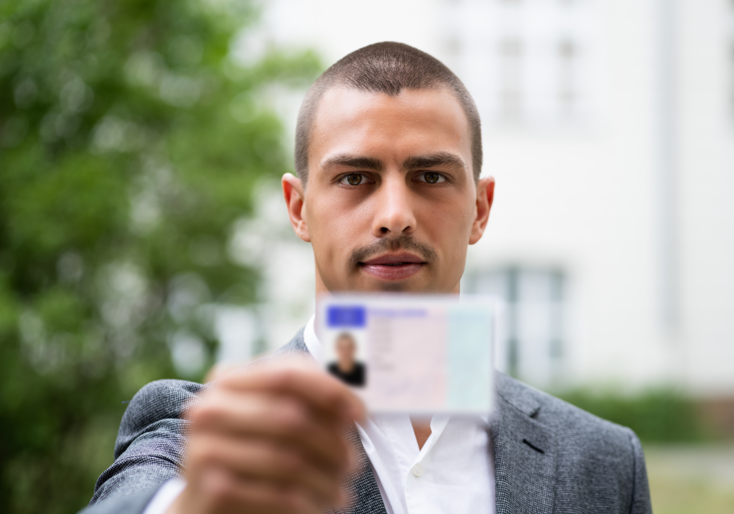 A man holding out a blurred ID card.