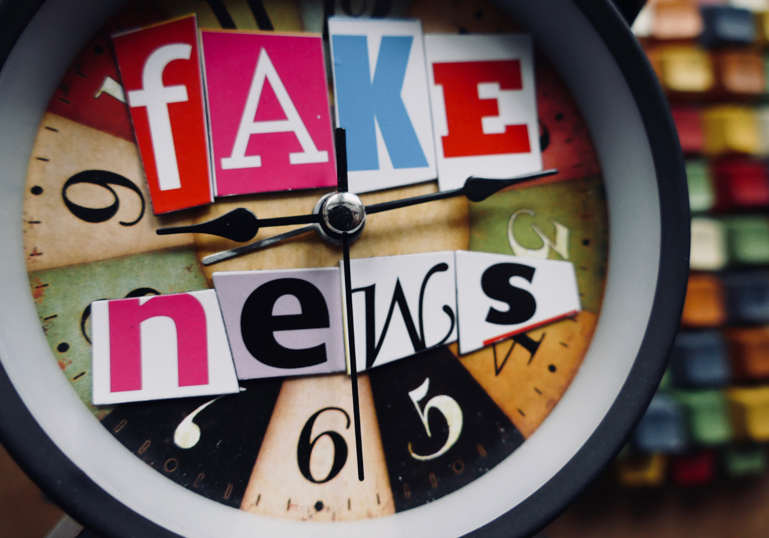 A clock with cutout letters from a magazine spelling out FAKE NEWS.