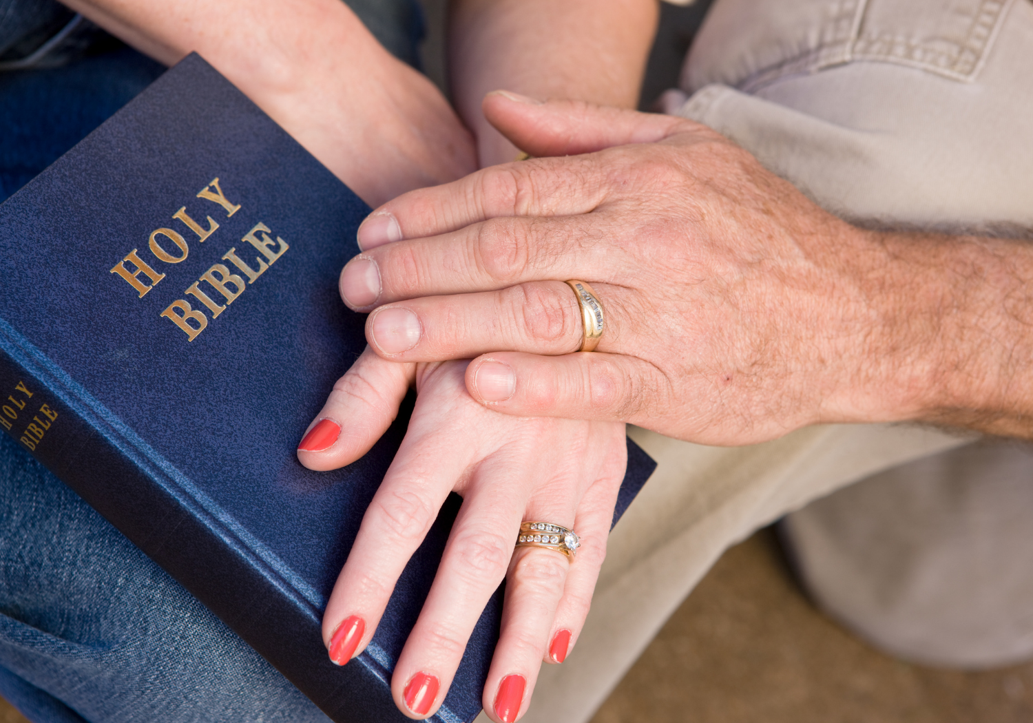 A couple's hands on top of a Bible.