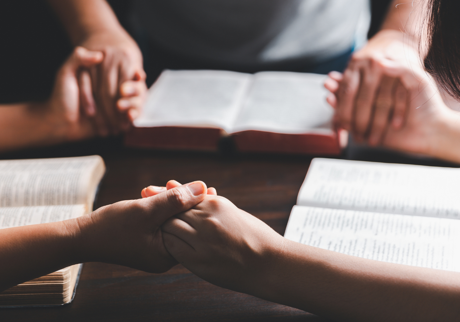A group of hands holding, with their Bibles open during worship.