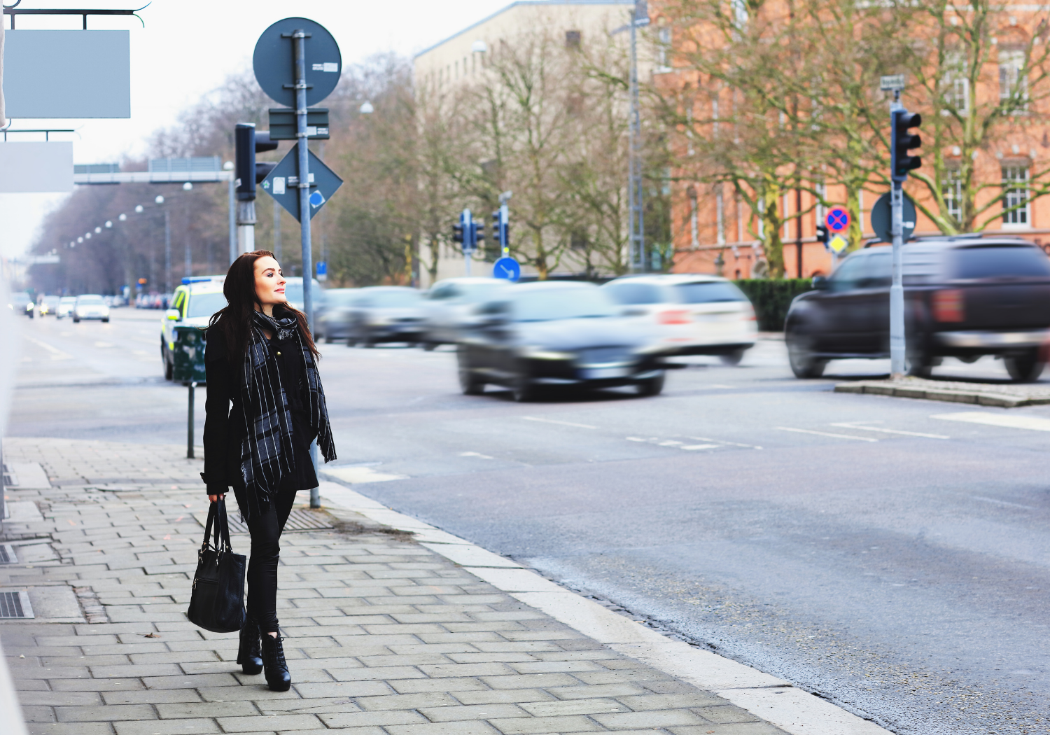 A woman walking on the side of the streets.