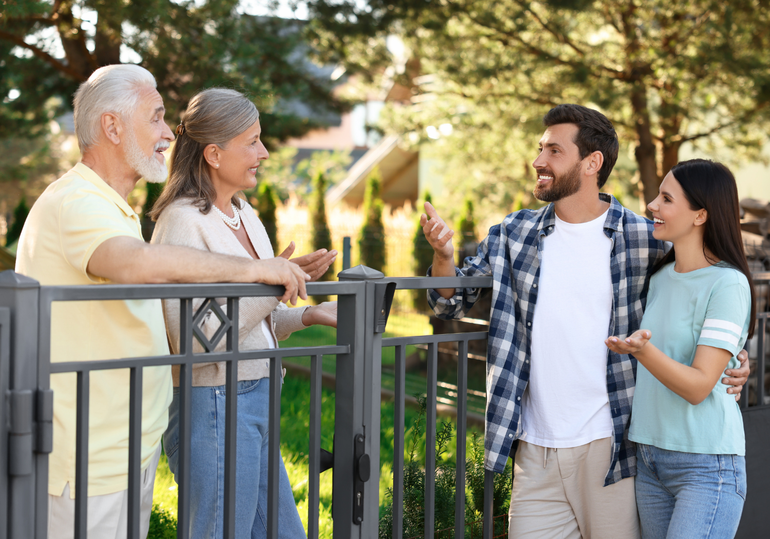 A pair of two couples, one older and the other younger, talking within a fence that separates them.