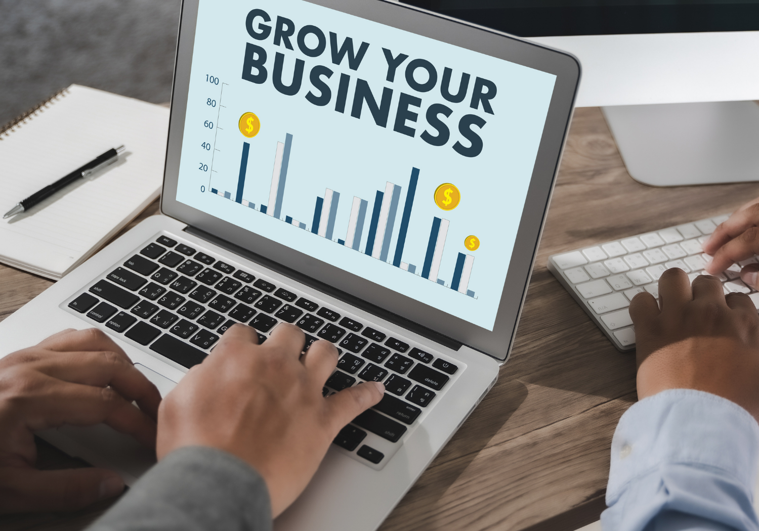 A person on a laptop, with a chart on screen and the words GROW YOUR BUSINESS.