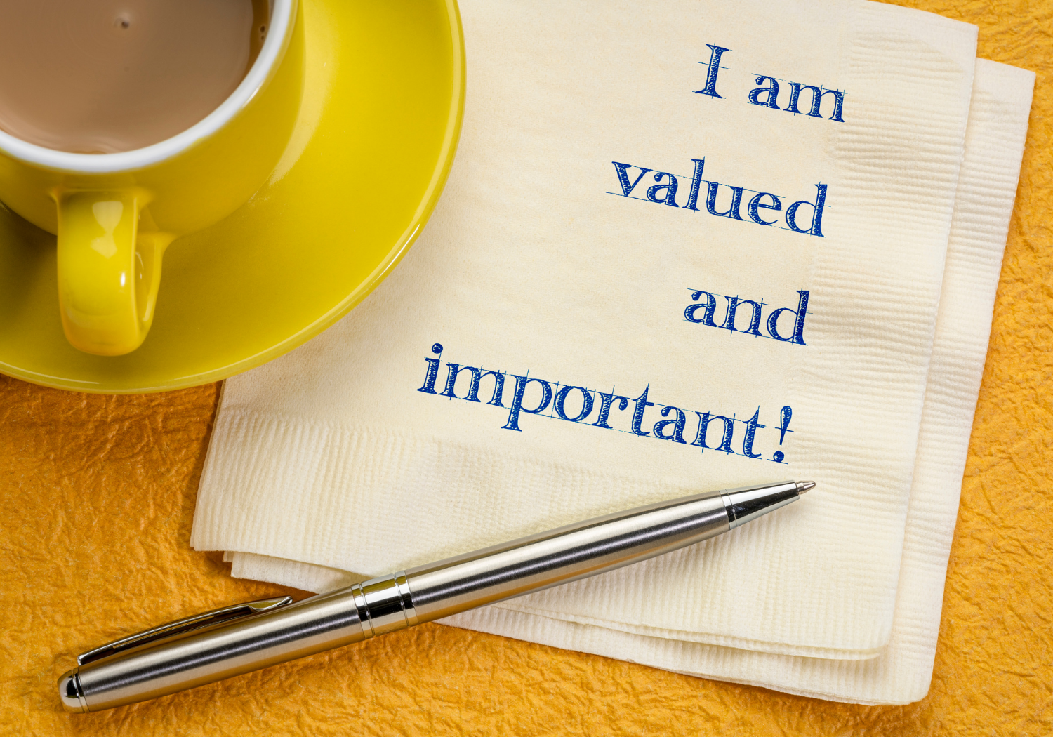 A table napkin with a cup of coffee on the side, with the words I AM VALUED AND IMPORTANT.