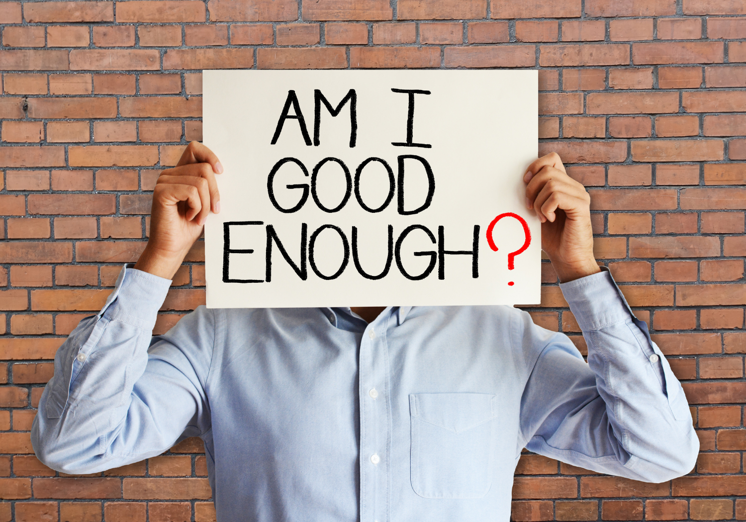 A person holding a placard with the words AM I GOOD ENOUGH?