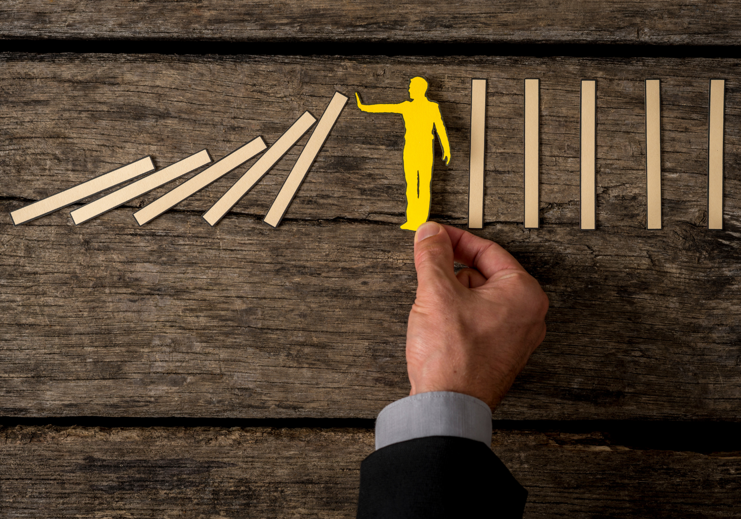 An image of a paper figure stopping midway in aligning wooden sticks.