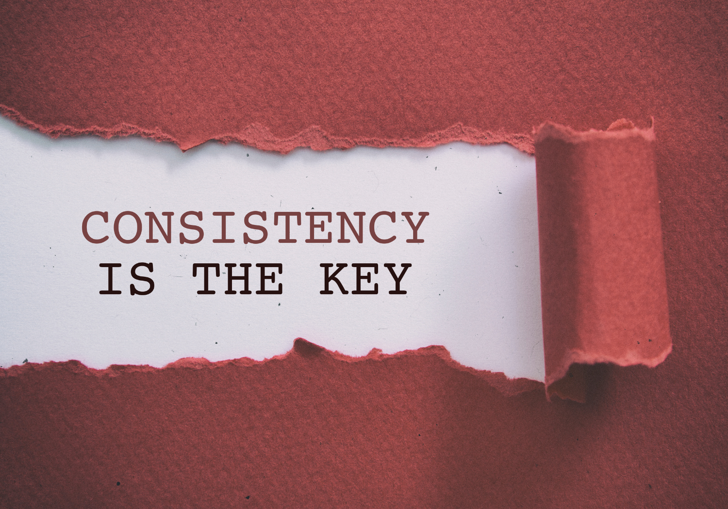 A part of a paper peeled, revealing the texts 'Consistency is the Key.'