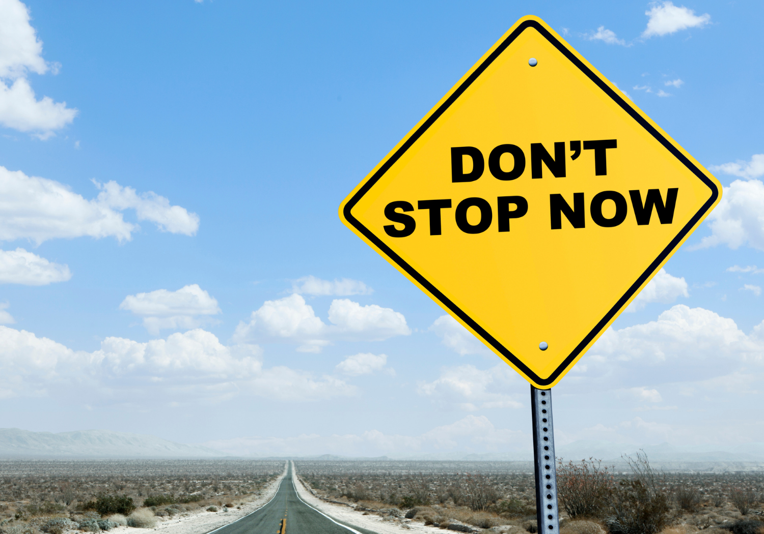 A road sign with the words "Don't Stop Now".