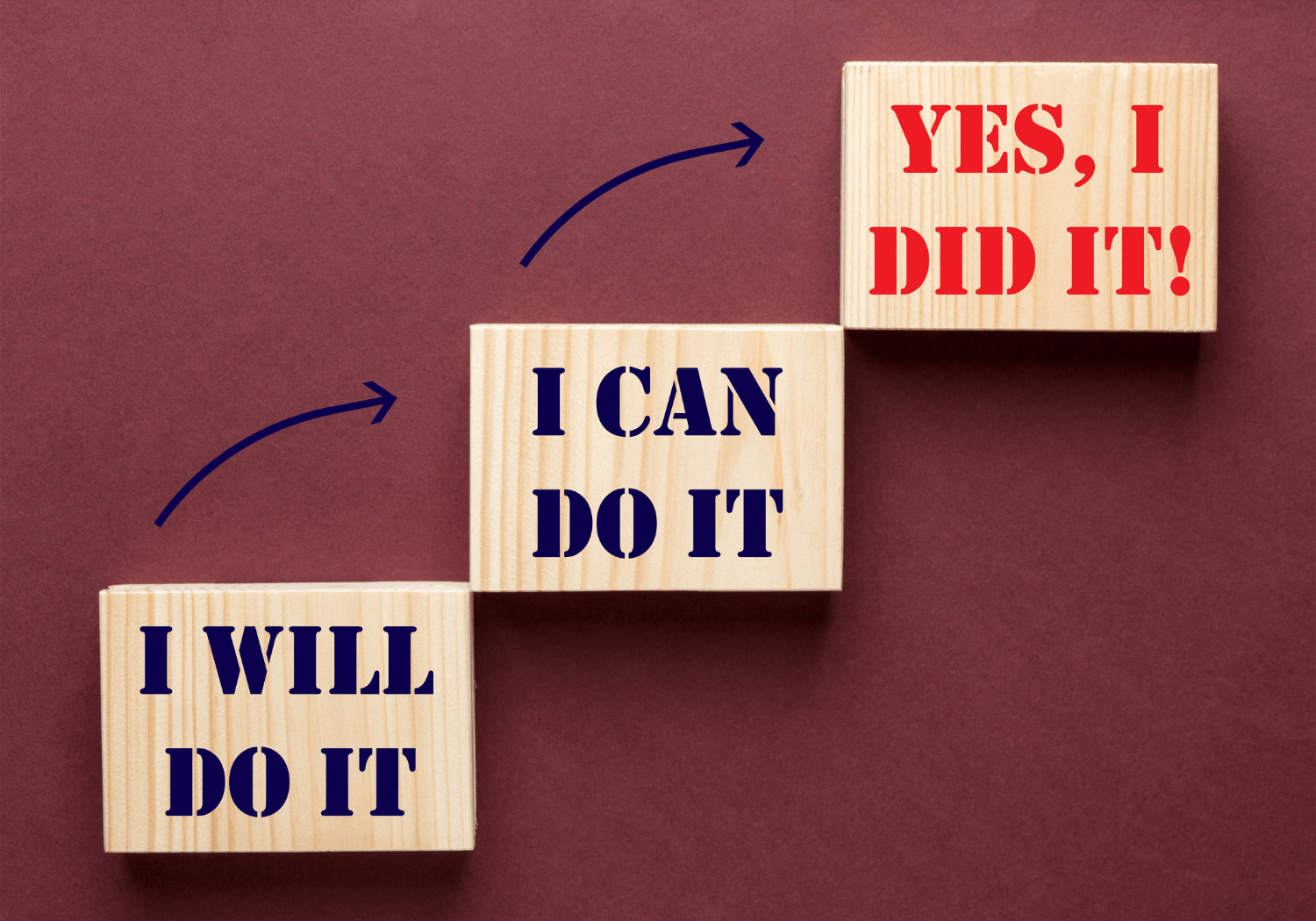 Three wooden blocks with the words "I WILL DO IT", "I CAN DO IT", and "YES, I DID IT!" signifying success.