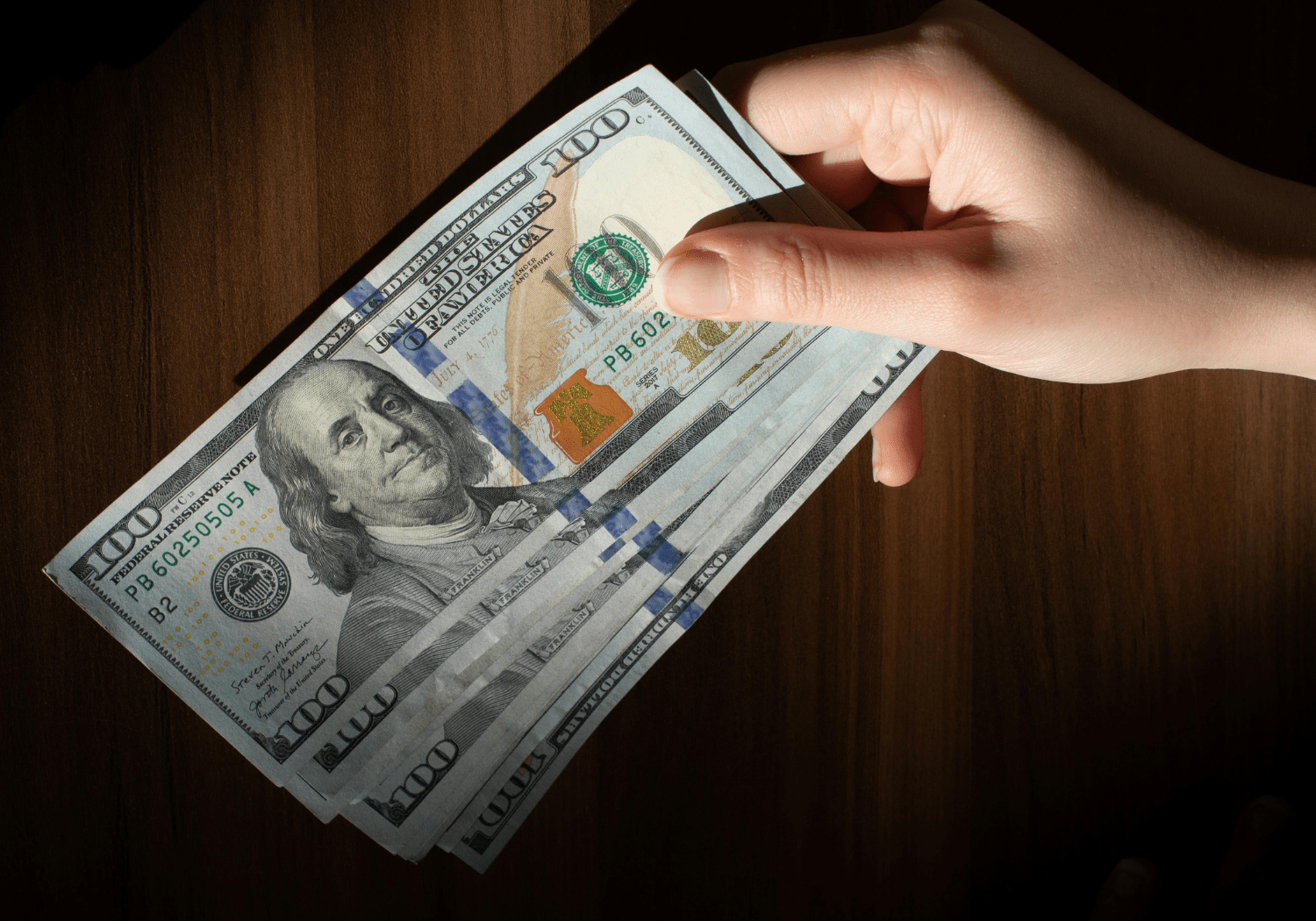 A person holding hundred dollar bills.