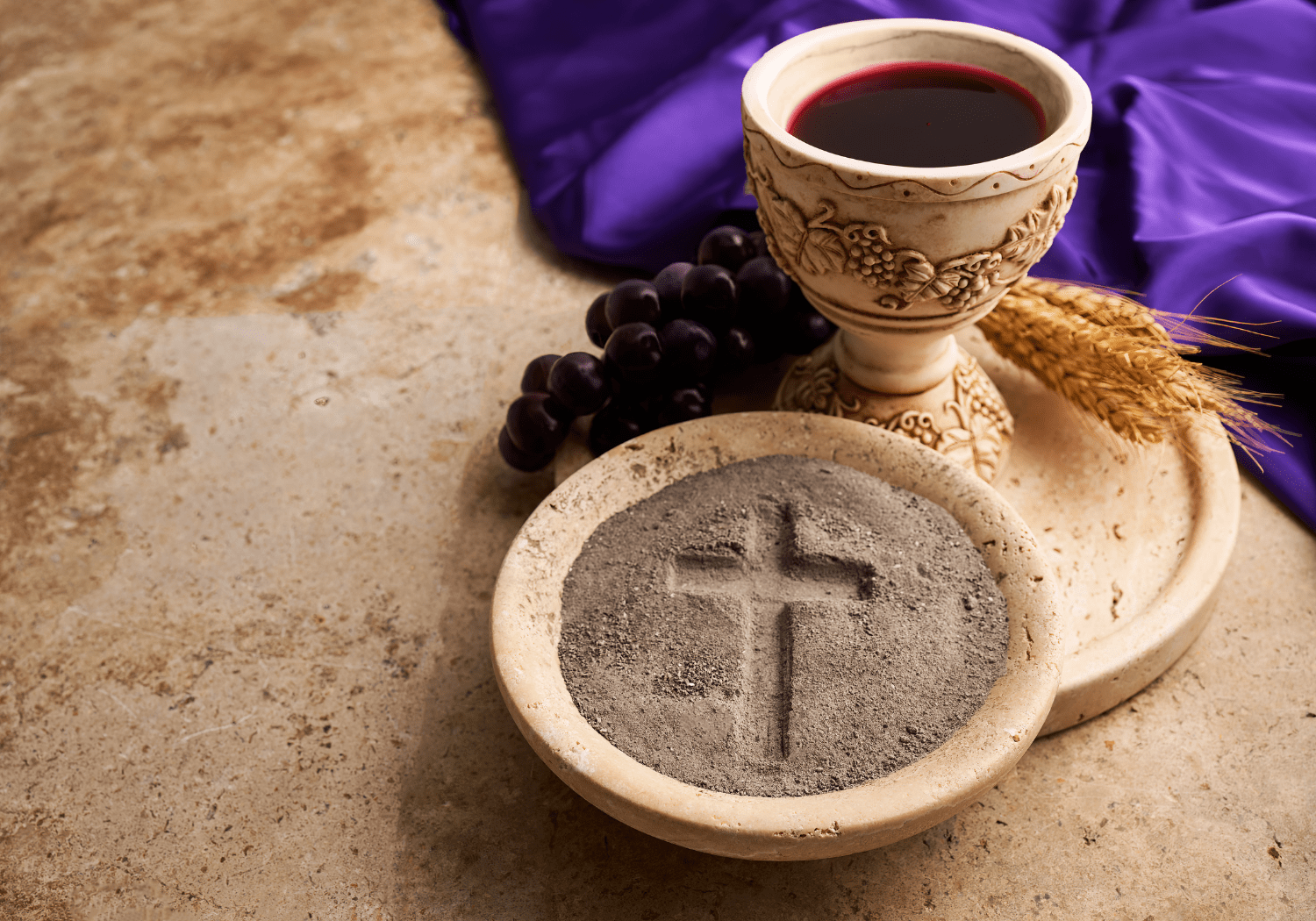 An image of a glass of red wine, and a cross carved on sand.