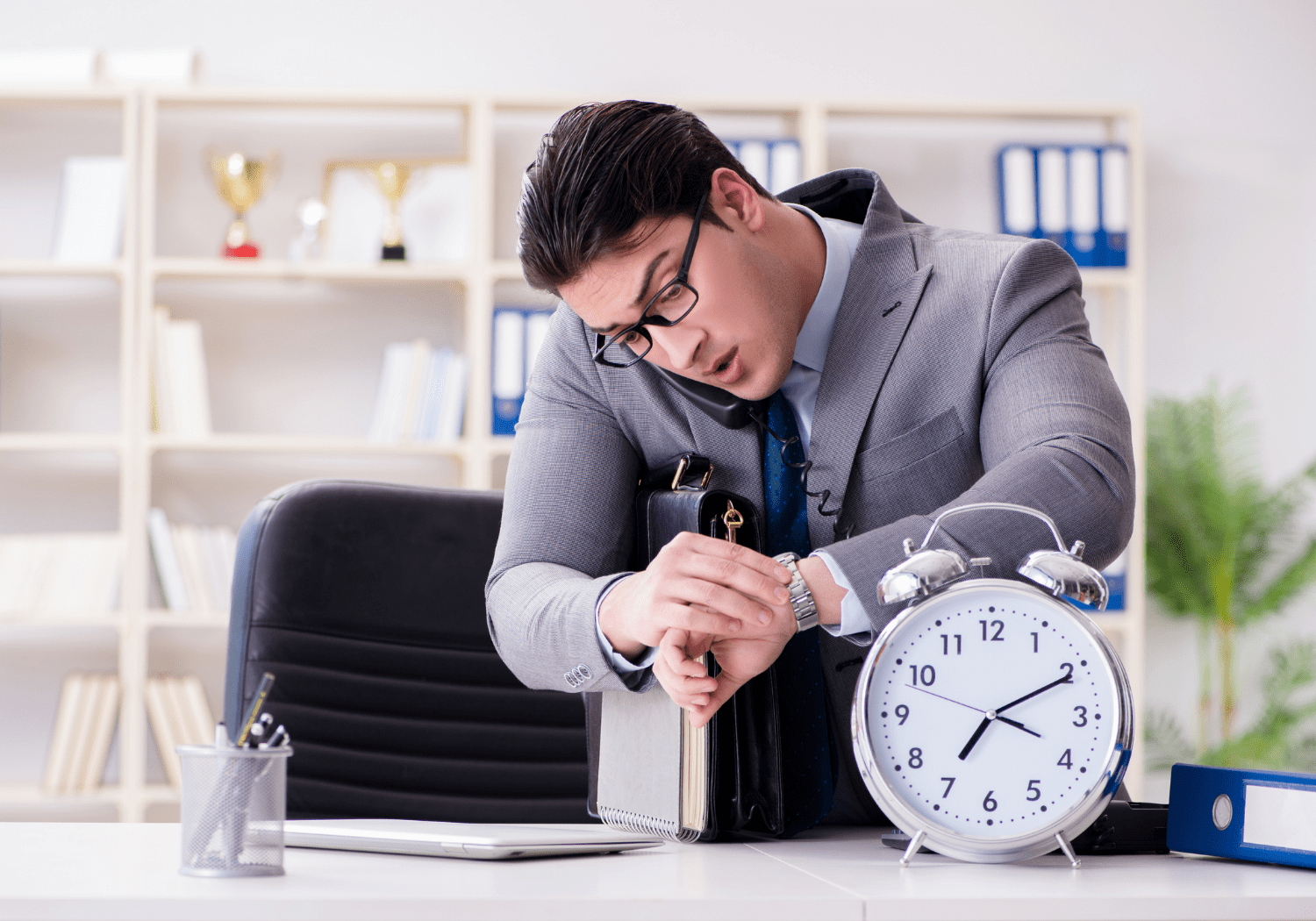 A man looking at his watch, with a big clock on the side.