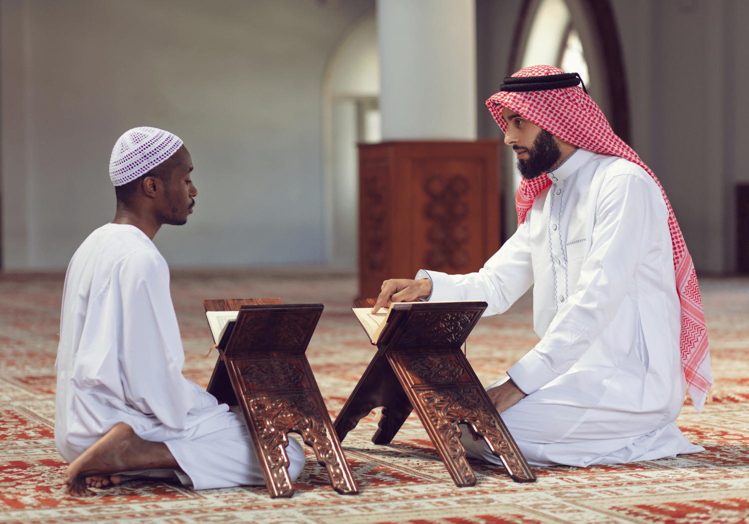 Two Muslim men studying the Quran inside a Mosque.