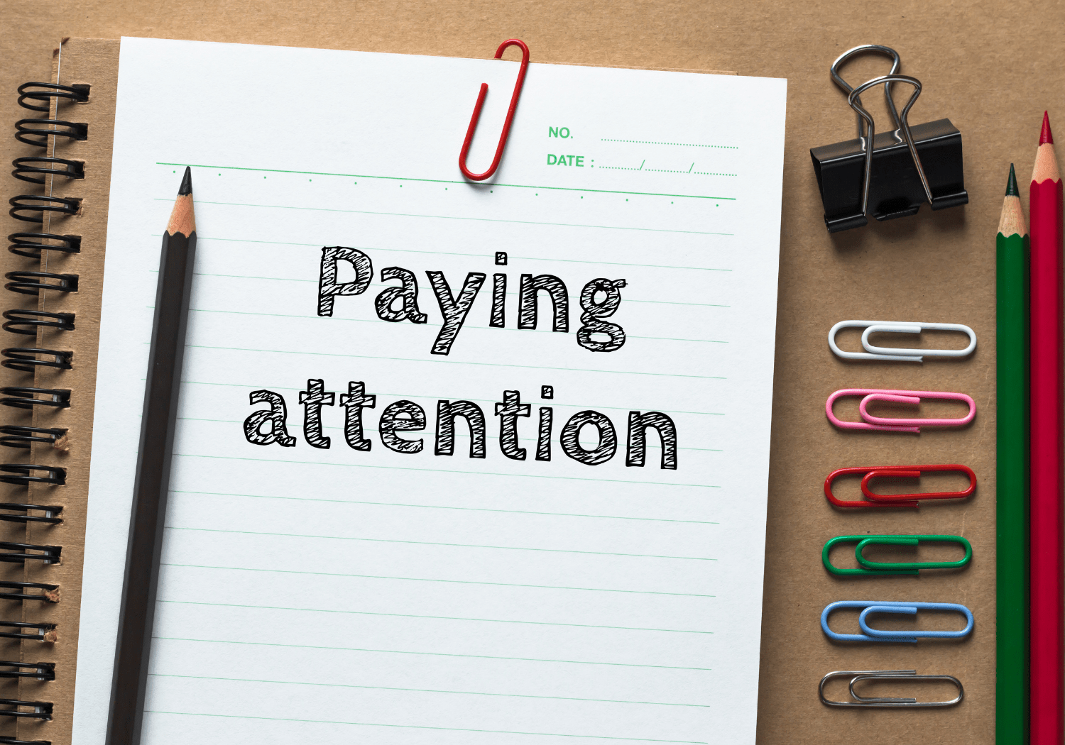 The words PAYING ATTENTION, written on a pad paper.