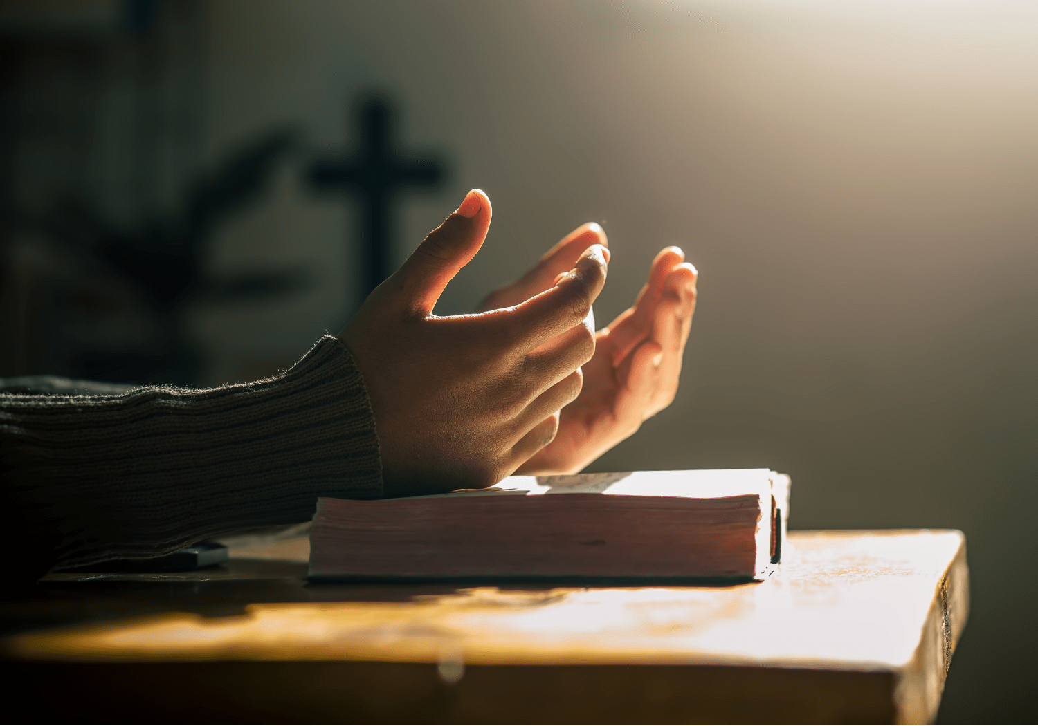A person raising his hands on top of a Bible.