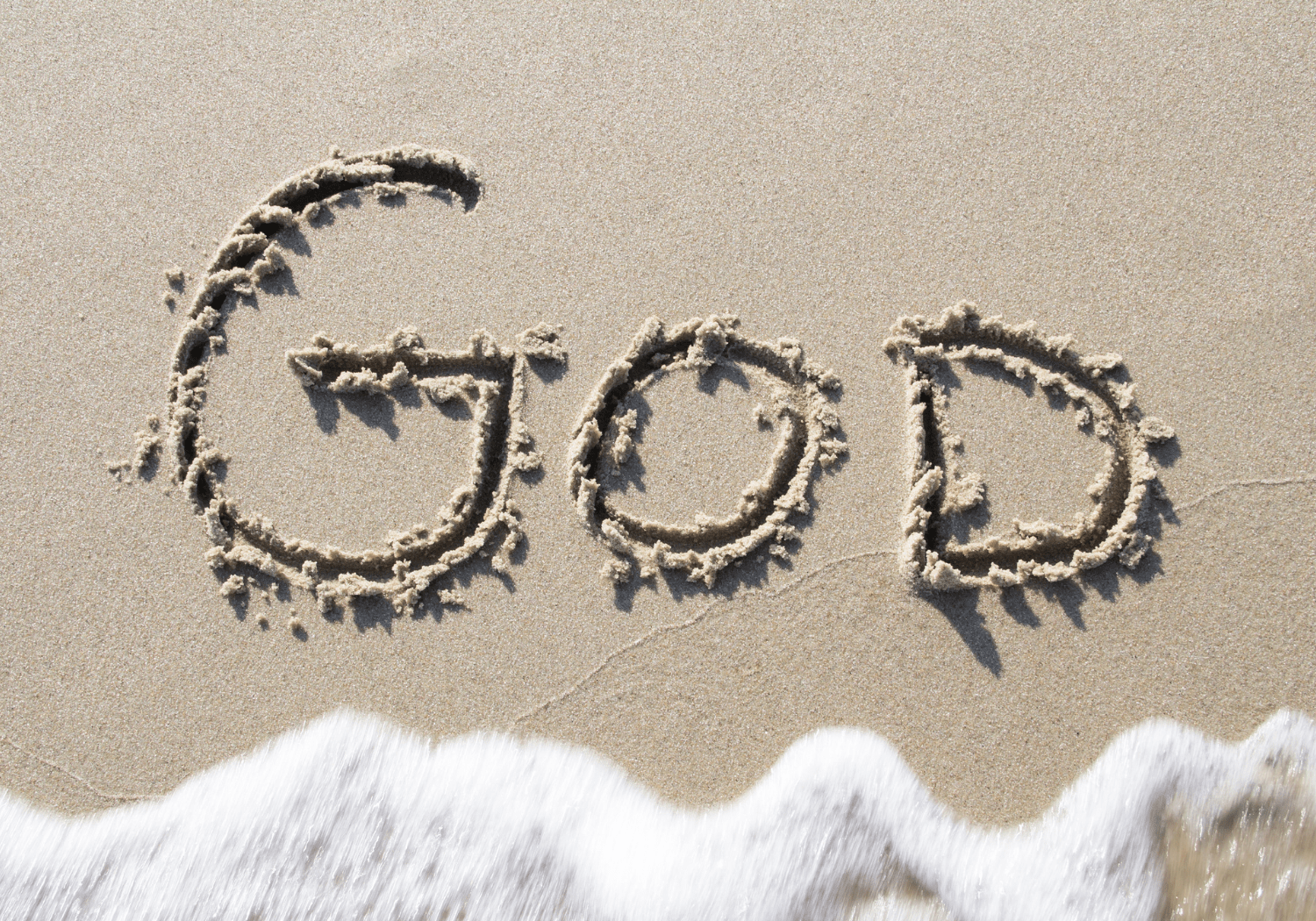 The word GOD written in the sand.
